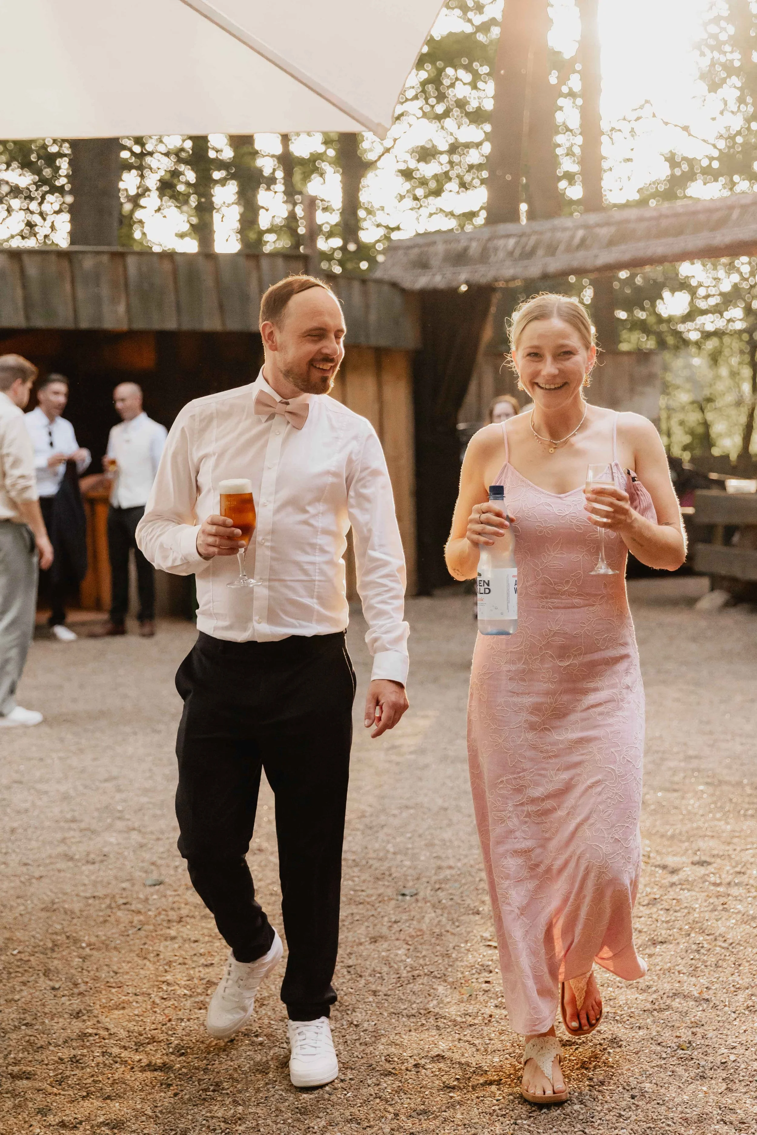 Frau im rosa Kleid und Mann mit Bierglas lachen beim Sektempfang