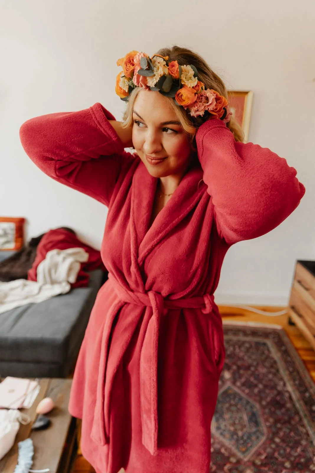Braut beim Getting Ready in Lüneburg wie sie sich ihren Blumenkranz richtet und im roten Bademantel vor dem Spiegel steht