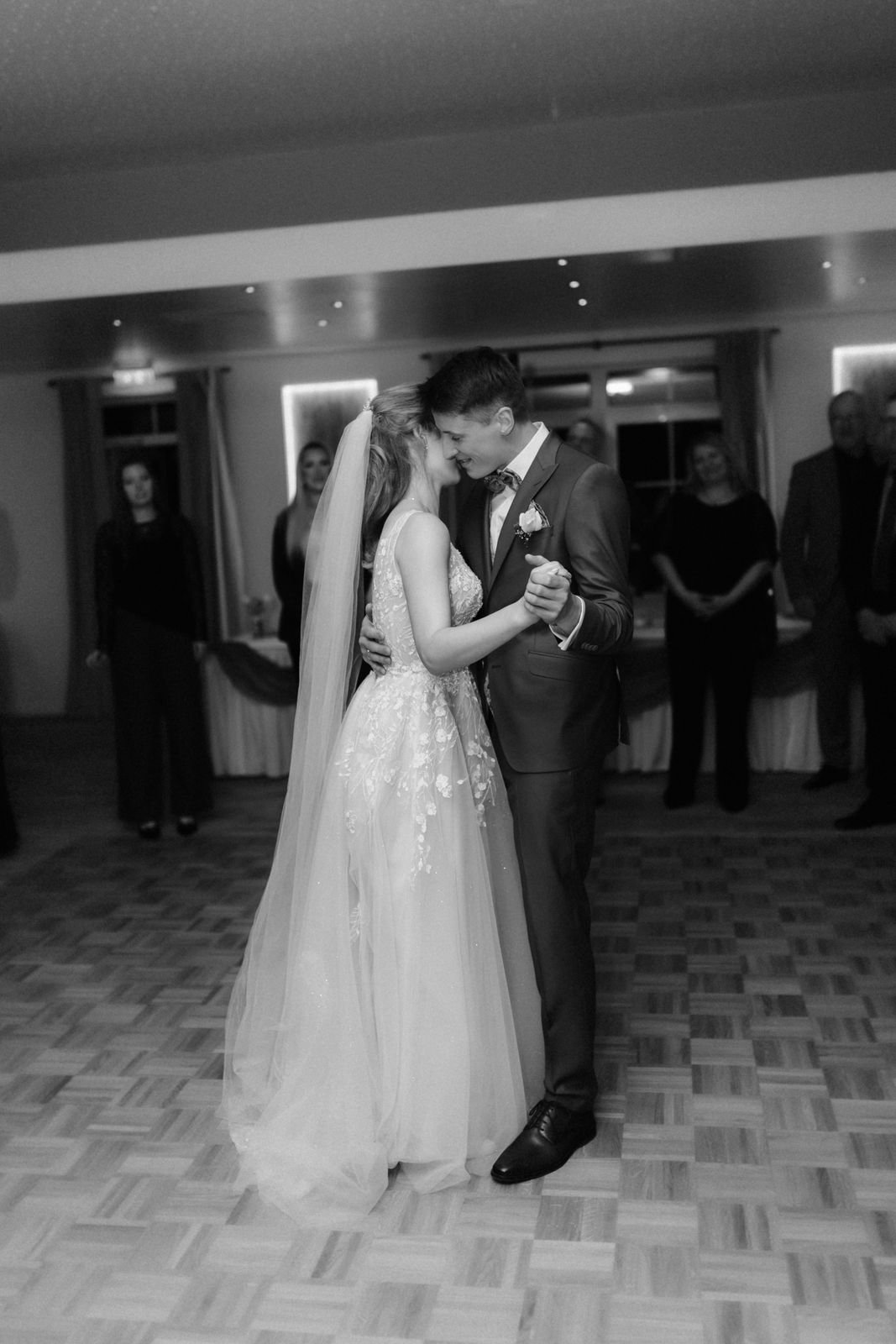 Brautpaar beim romantischen Hochzeitstanz in einem festlichen Saal, fotografiert in Schwarz-Weiß