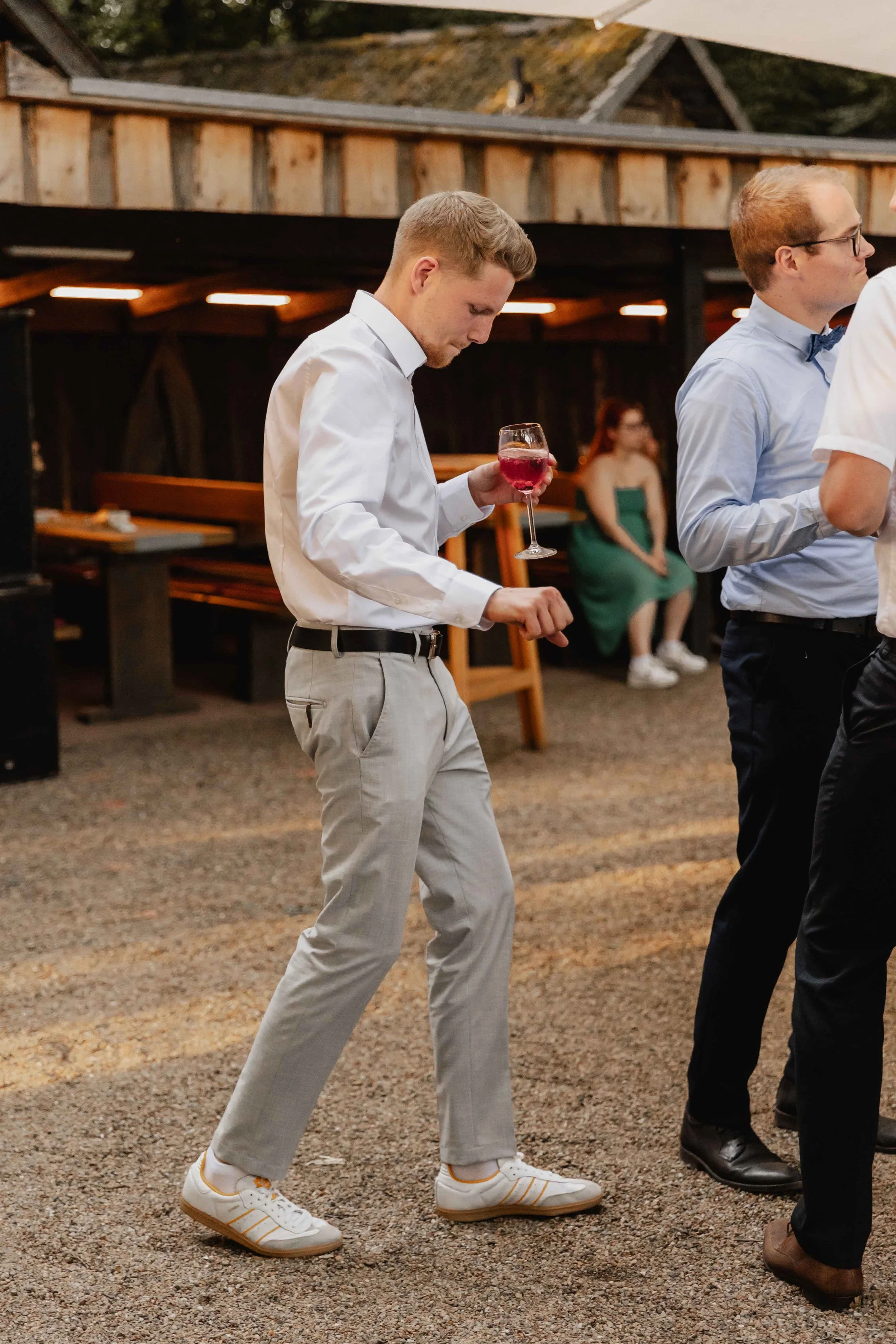Mann tanzt mit Glas in der Hand bei der Feier im Hofbereich