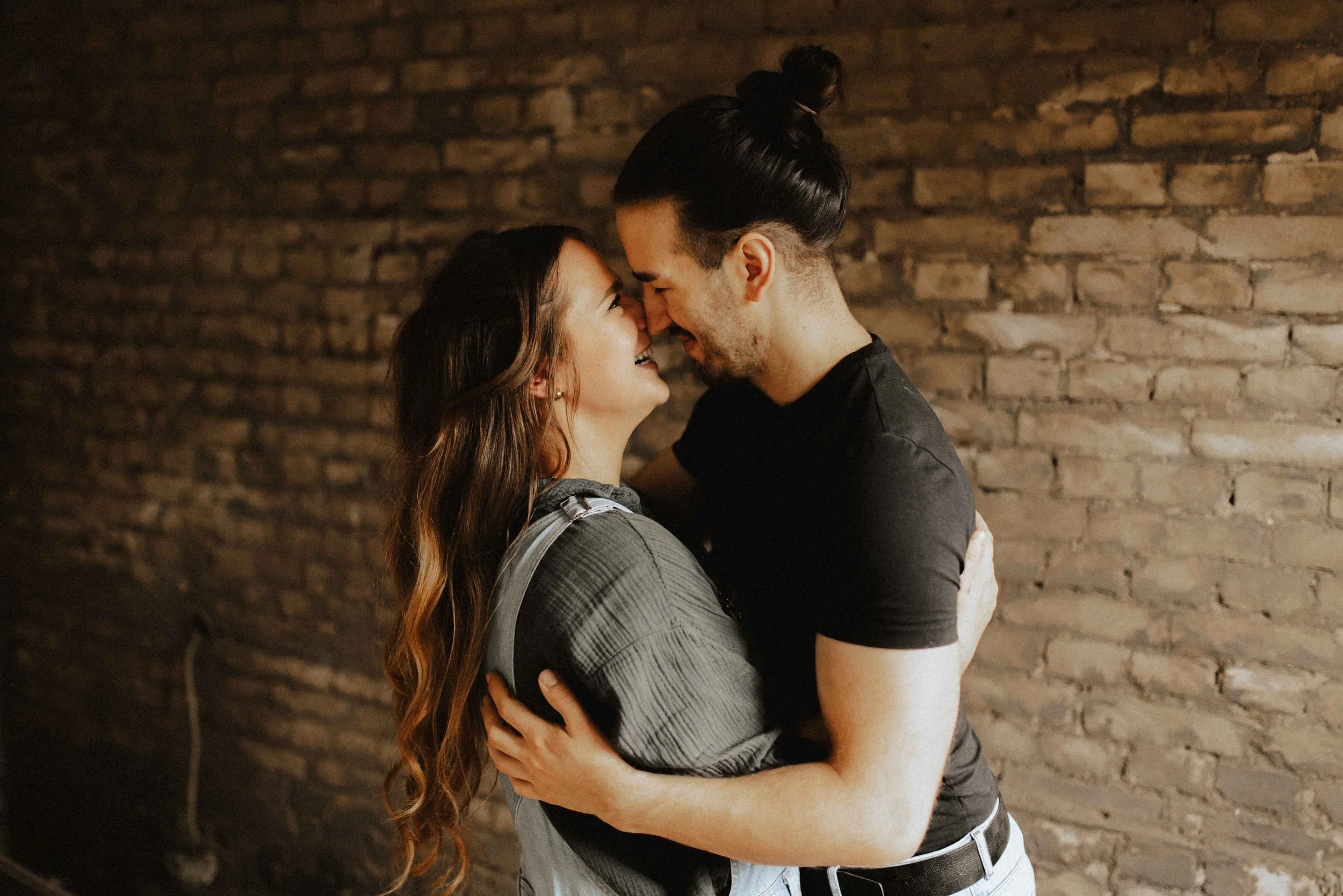 Paarshooting auf Baustelle – inniger Moment mit Stirn an Stirn vor Backsteinwand in Lüneburg.