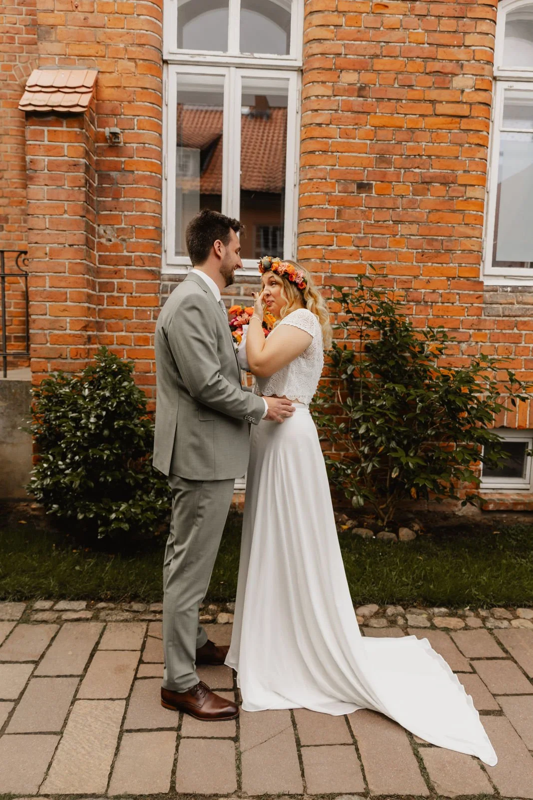 Zärtlicher Moment beim First Look des Brautpaares vor einer Backsteinfassade während der Hochzeit in Lüneburg