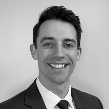 Black-and-white portrait of a smiling man in a suit and tie.