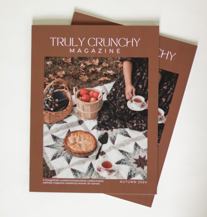 Truly Crunchy Magazine cover featuring a picnic scene with a quilt, basket of apples, pie, and person holding a tea cup. Autumn 2024 issue.