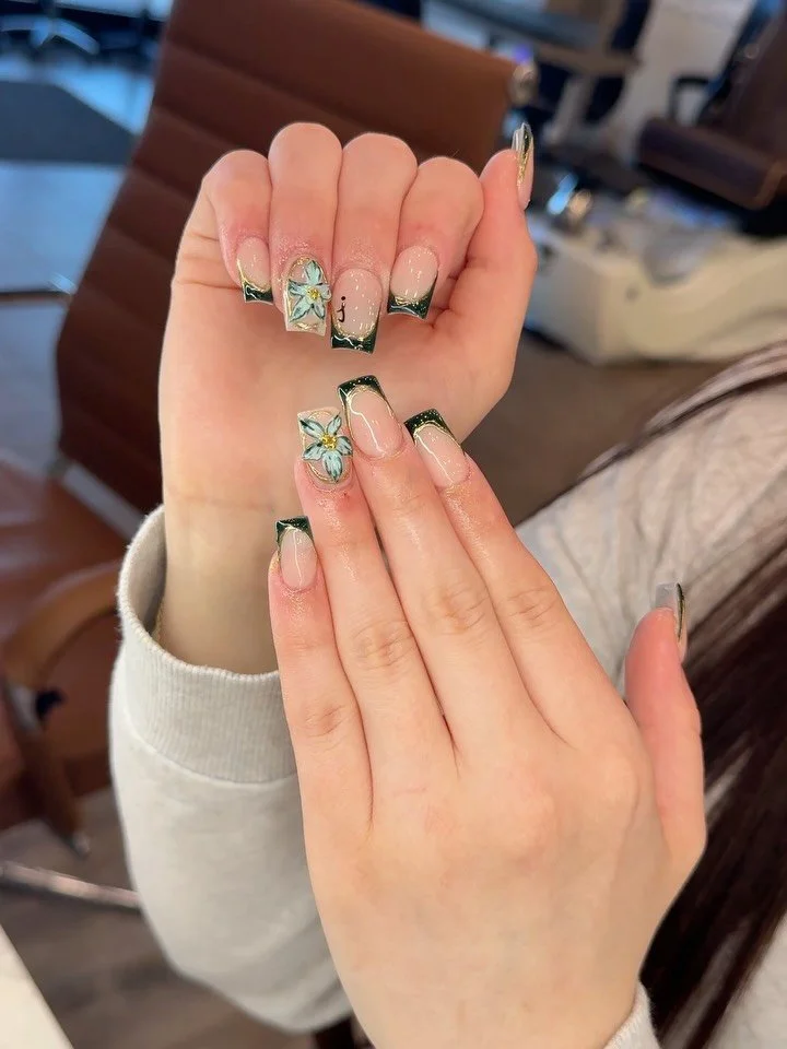 Elegant with a bold edge ✨🖤

This French tip set brings together luxury and artistry with hand-painted floral details, delicate gold accents, and glossy nude bases for the perfect balance of classy and chic. The 3D flower charms add just the right t