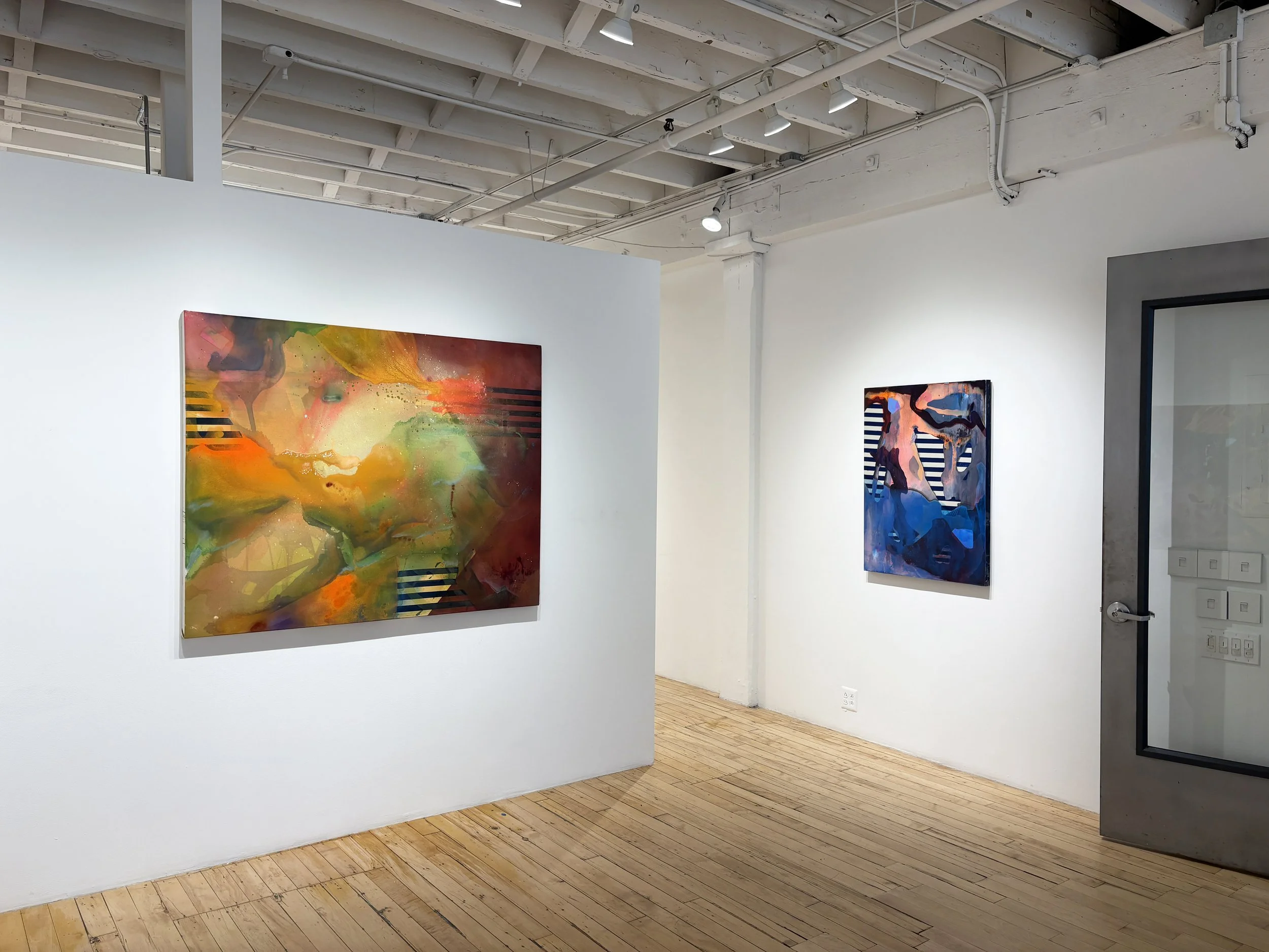 Two abstract paintings displayed on white gallery walls in a modern art exhibition space.