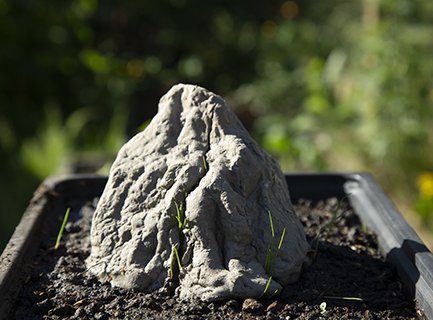 Photograph of cast clay mountain with grass seeds starting to grow.
