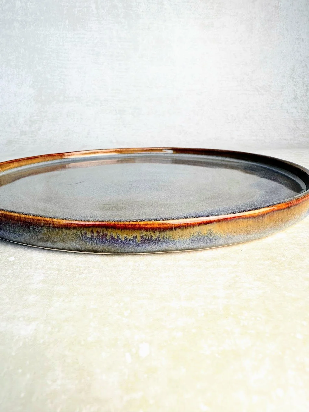 Round ceramic platter with a glazed surface and earthy tones.