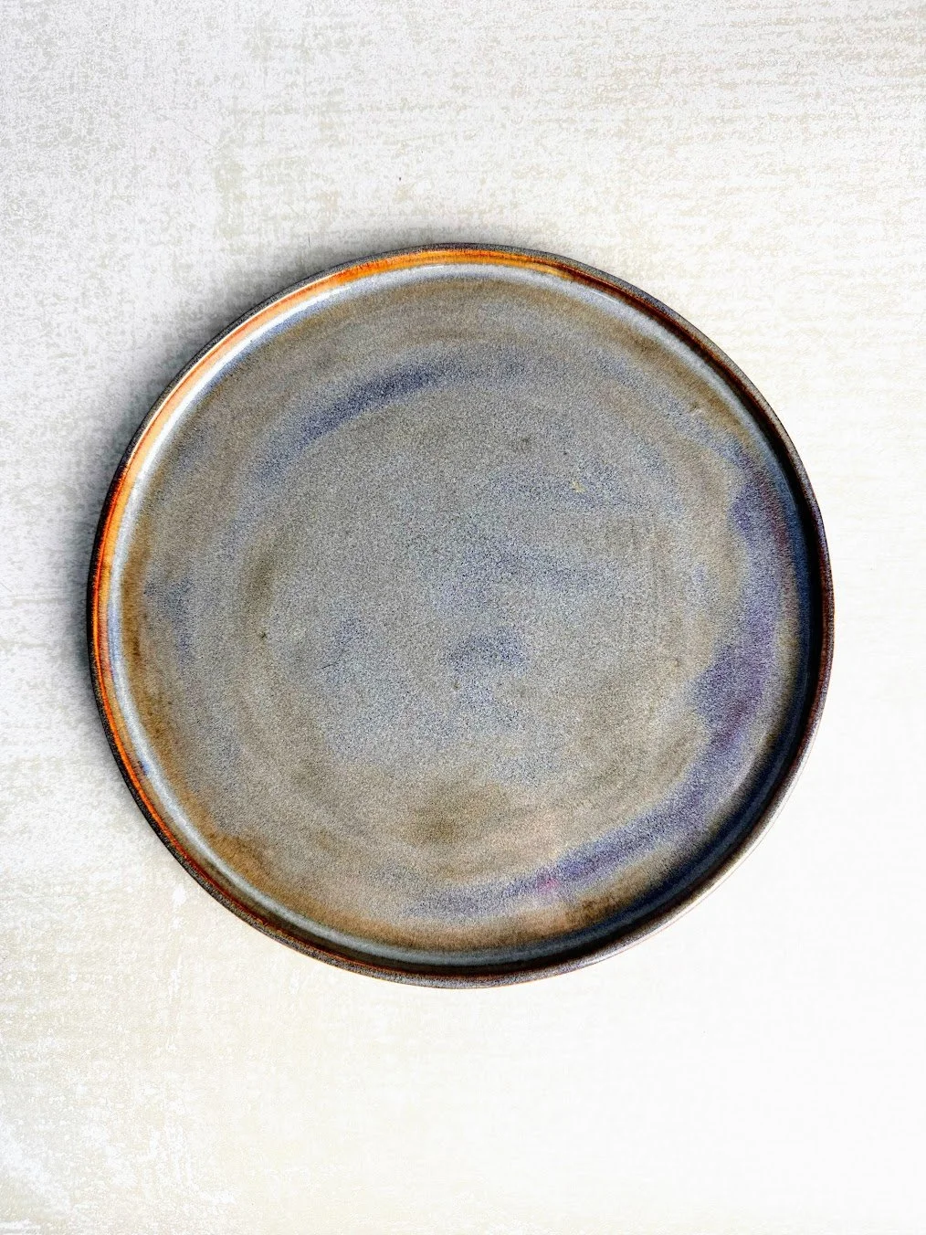 Gray ceramic plate with a subtle gradient, empty, on a light textured surface.