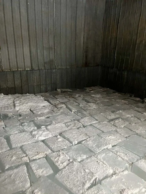 Corner of a room with gray brick flooring and wooden paneled walls.