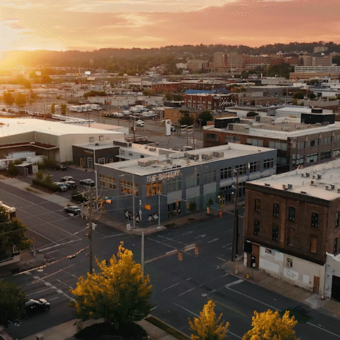 Aerial view of a city at sunset showing streets, buildings, and trees.