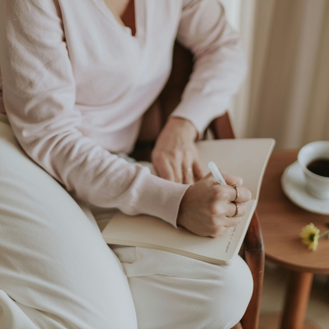 Adult journaling in a calm, natural setting, symbolizing reflection and intentional growth.