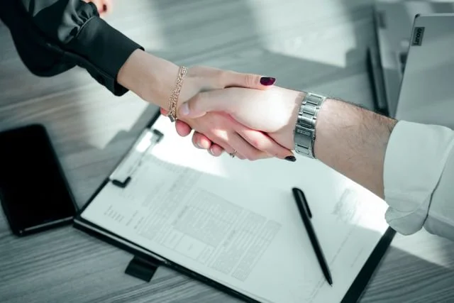 Close-up of a professional handshake over a contract