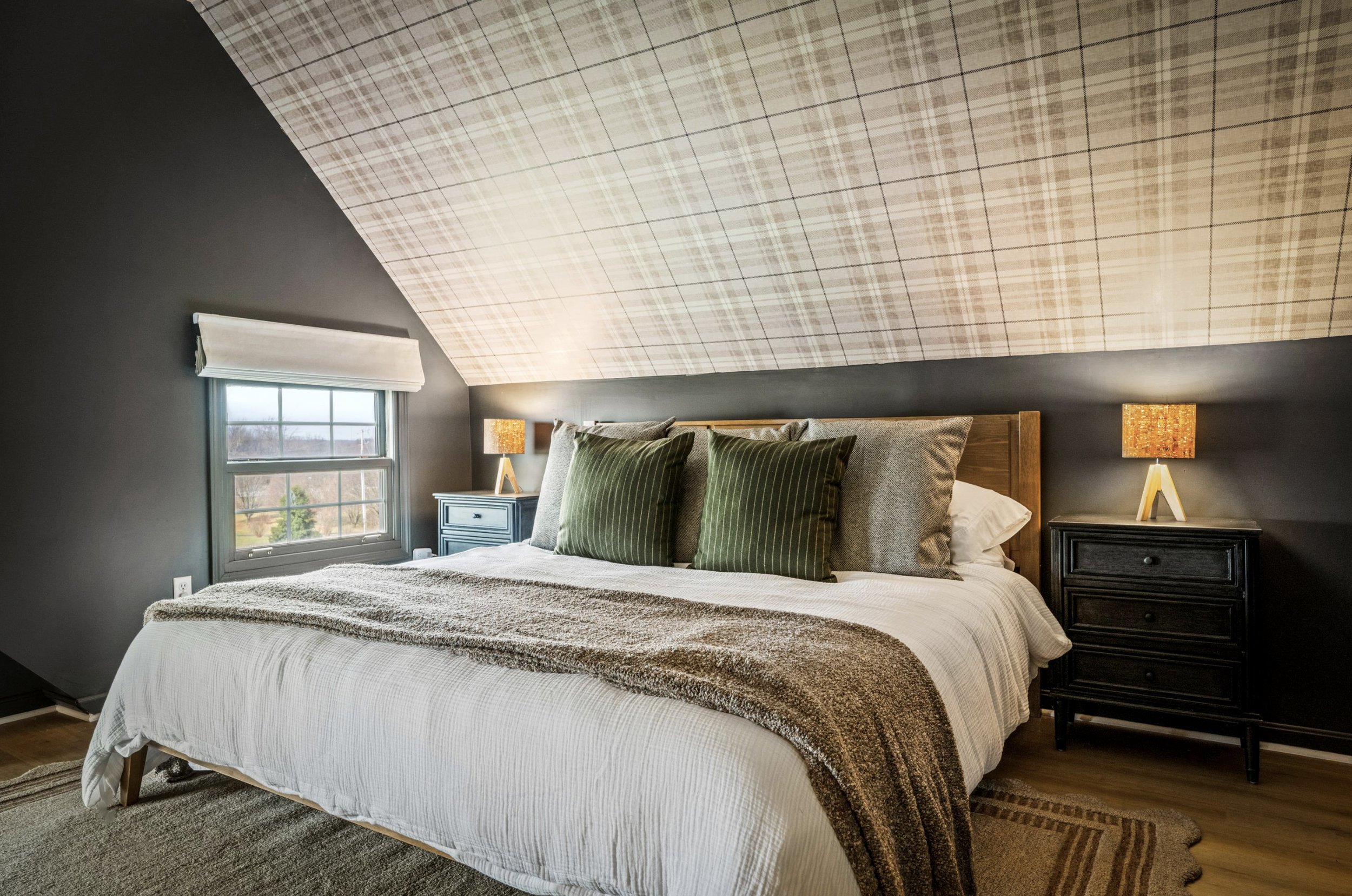 Moody bedroom design with plaid wallpaper on the slanted ceilings.