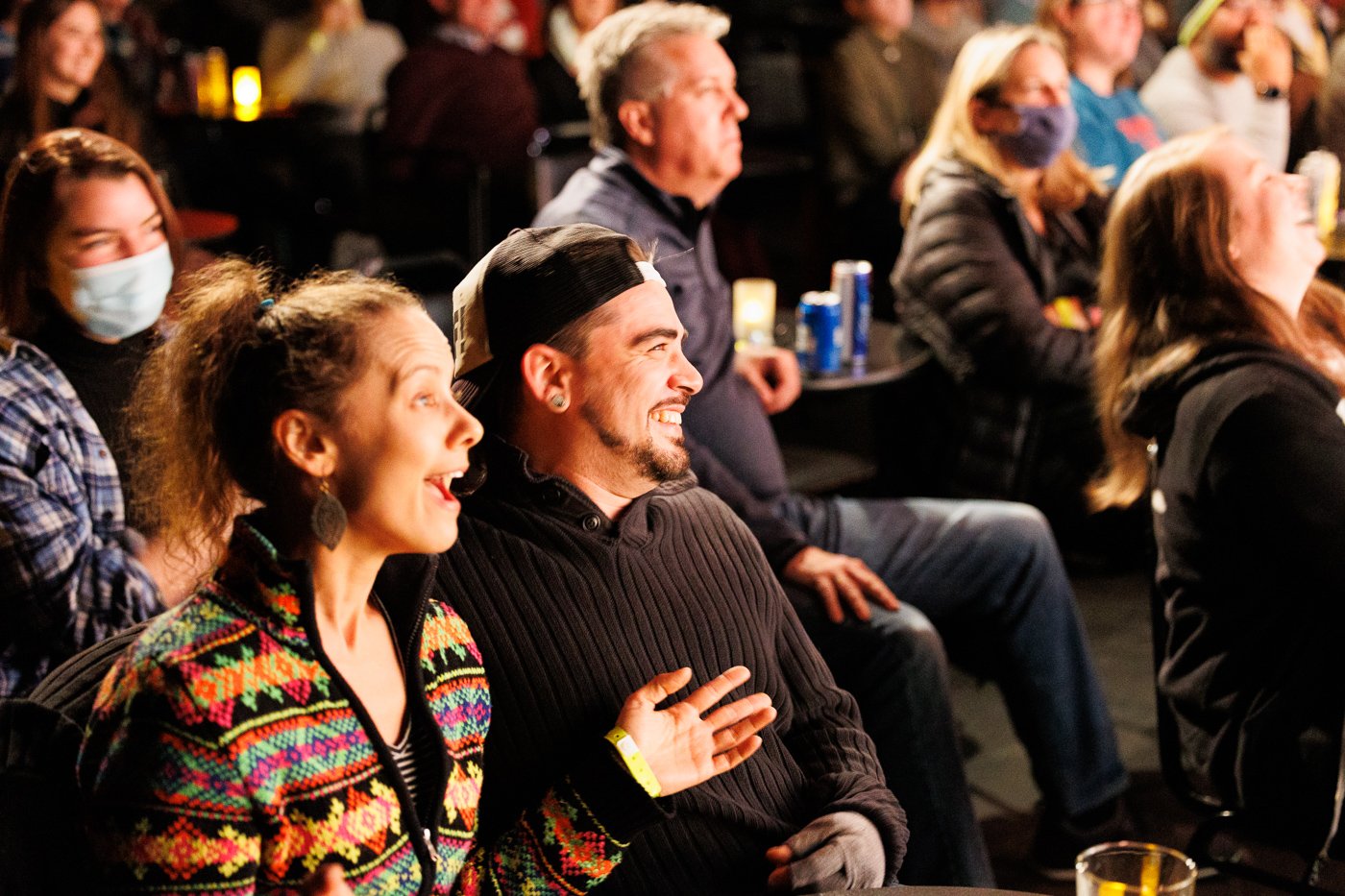 A group of people sitting at a comedy show, laughing and enjoying the performance.