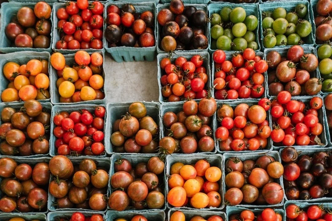 Various types of heirloom tomatoes in small baskets at a market