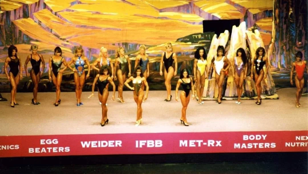 Inaugural Ms Fitness Olympia 1995
Sharon Bruneau (far Left in back row) 
Front is Saryn Muldrow and Carol Semple in center (3rd. Athlete unknown)
Can detect Debbie Kruck, Mia Finnigan, Madonna Grimes, Milamar Flores and very end far right is Penny Pr