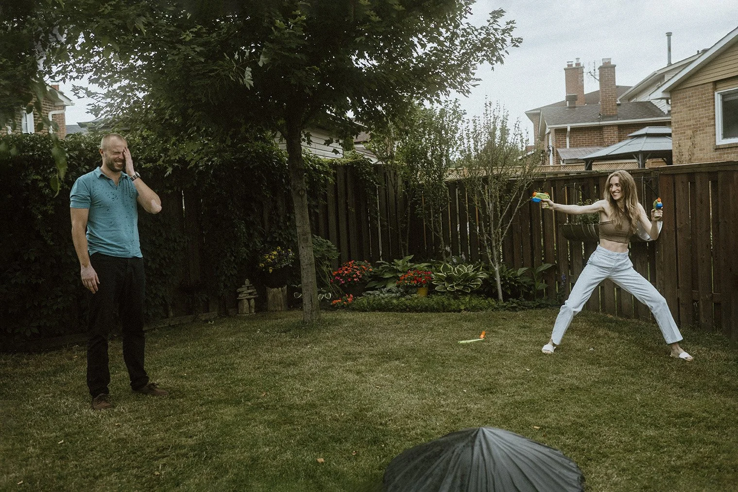 Older teen siblings are playing with water guns in their backyard