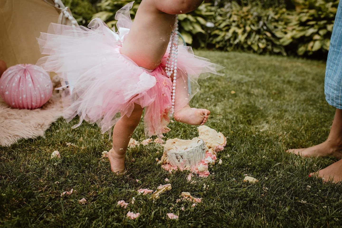 Candid cake smash photo of a child's first birthday and walking on their cake. 