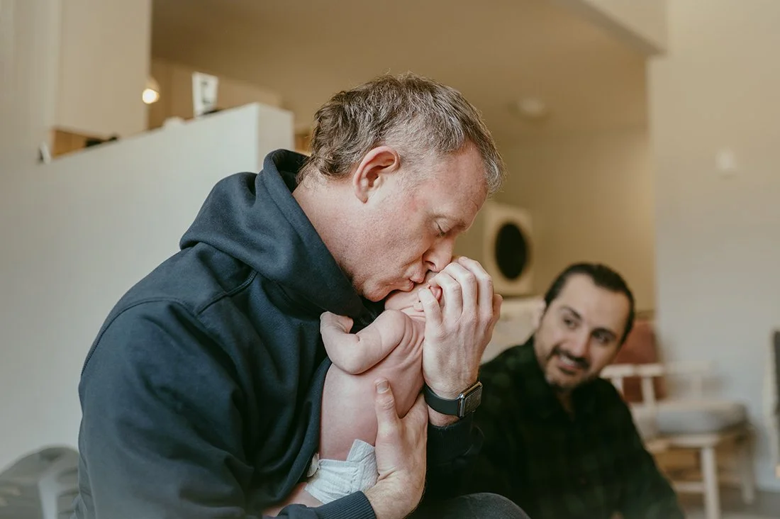 Queer family of two dads with newborn baby in a toronto home