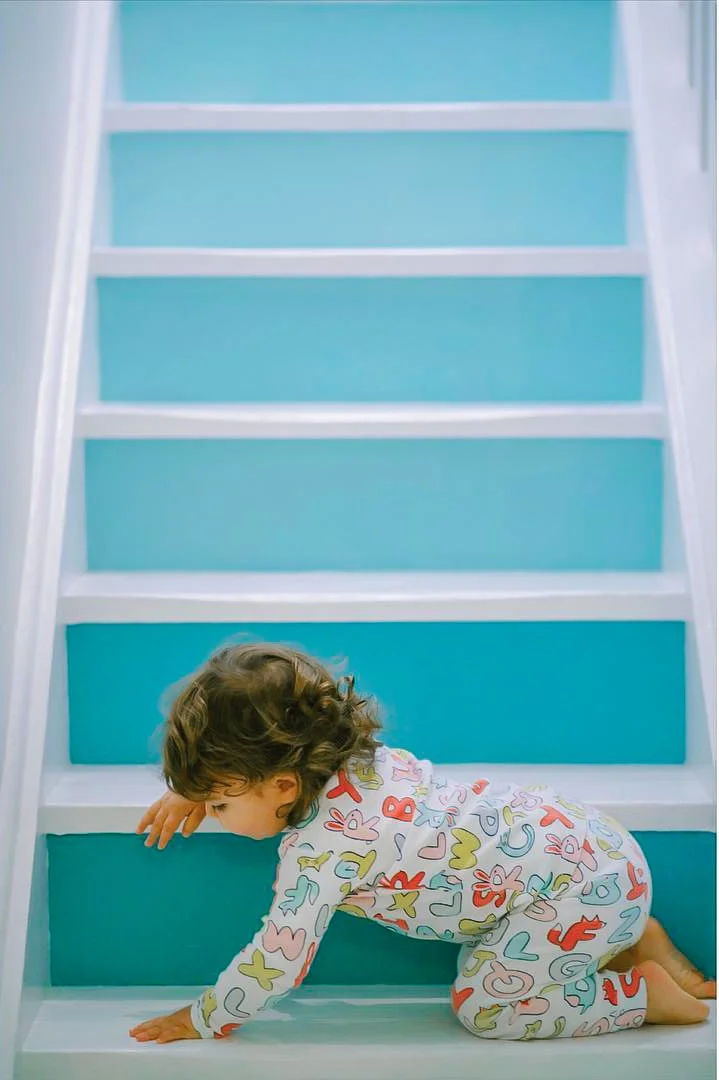 Child crawling on the bottom of a blue staircase