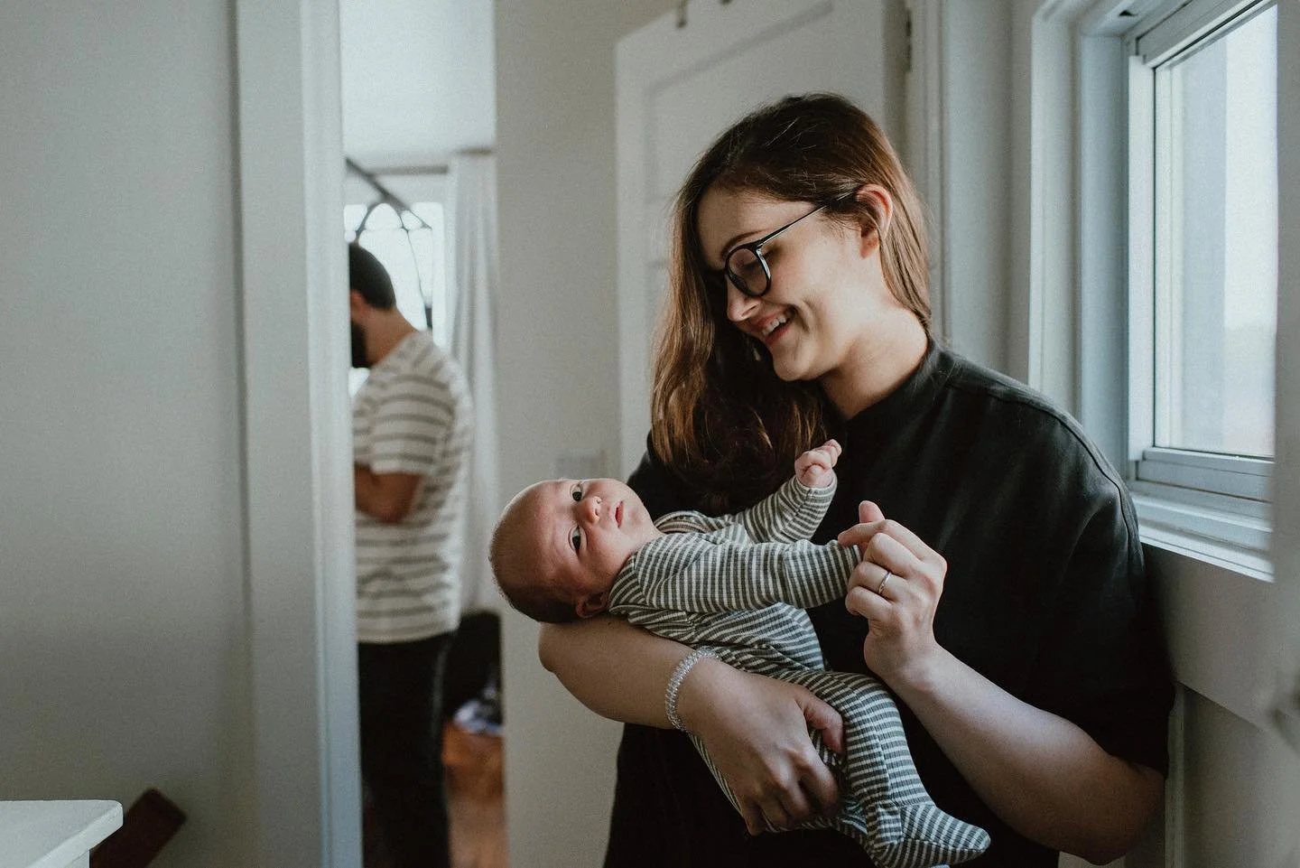 Mother in her home in toronto leslieville holding her newborn baby and smiling