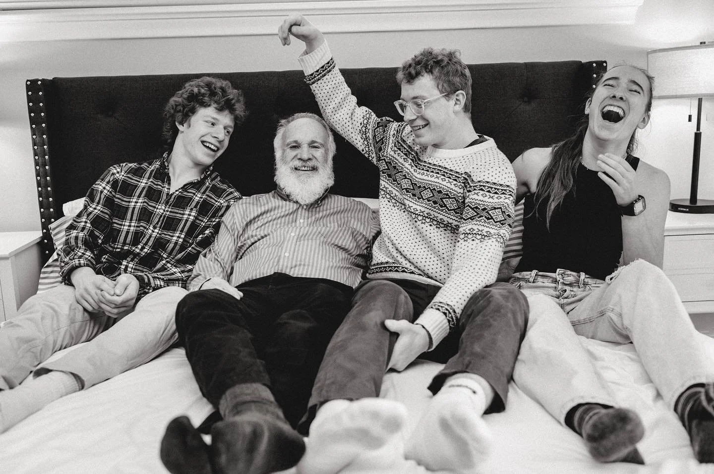 A black and white candid photo of older teens laughing with their grandpa in a house by the Danforth in Toronto