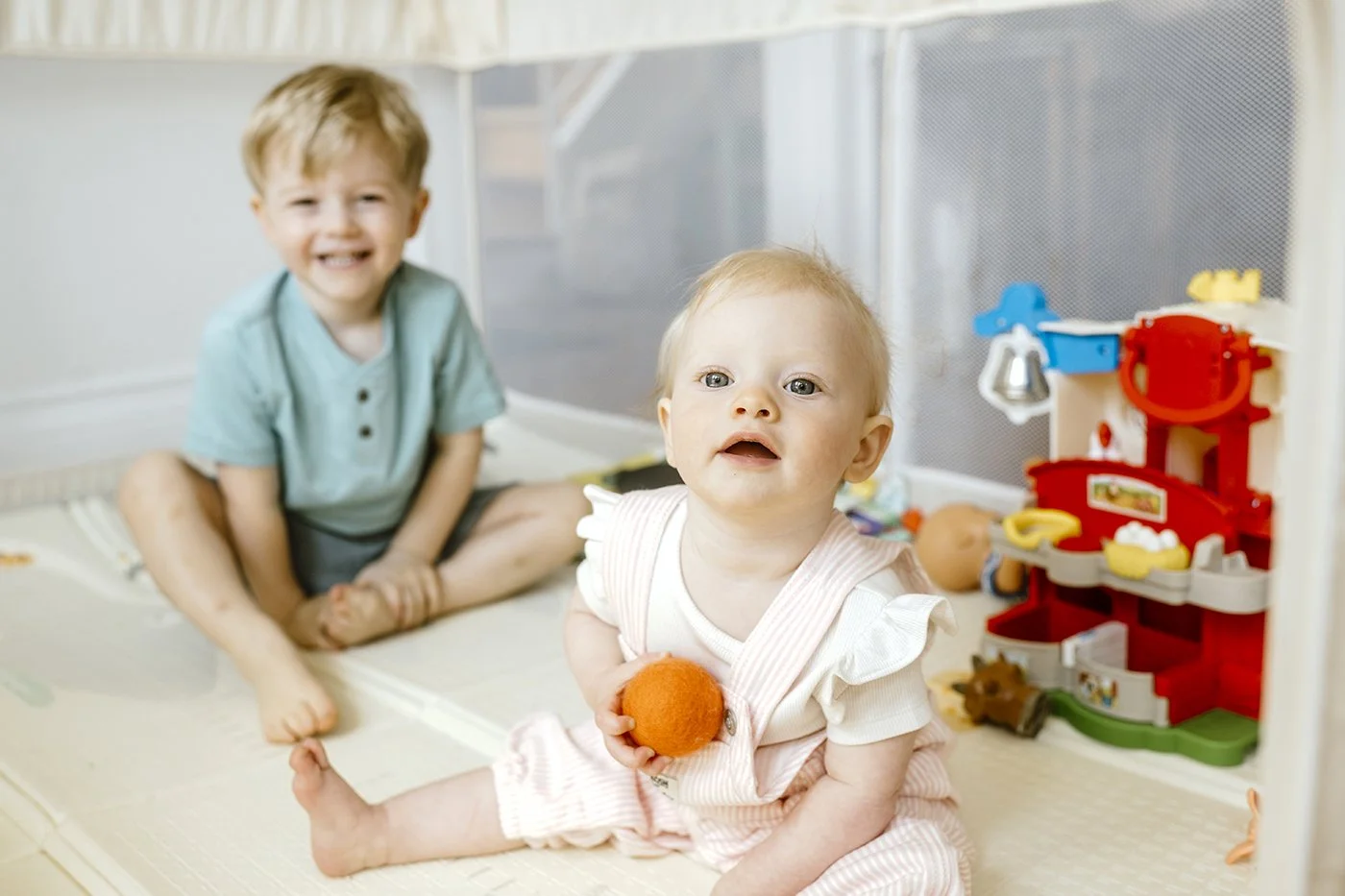 candid family photography photo of a brother and sister at home in their play pen