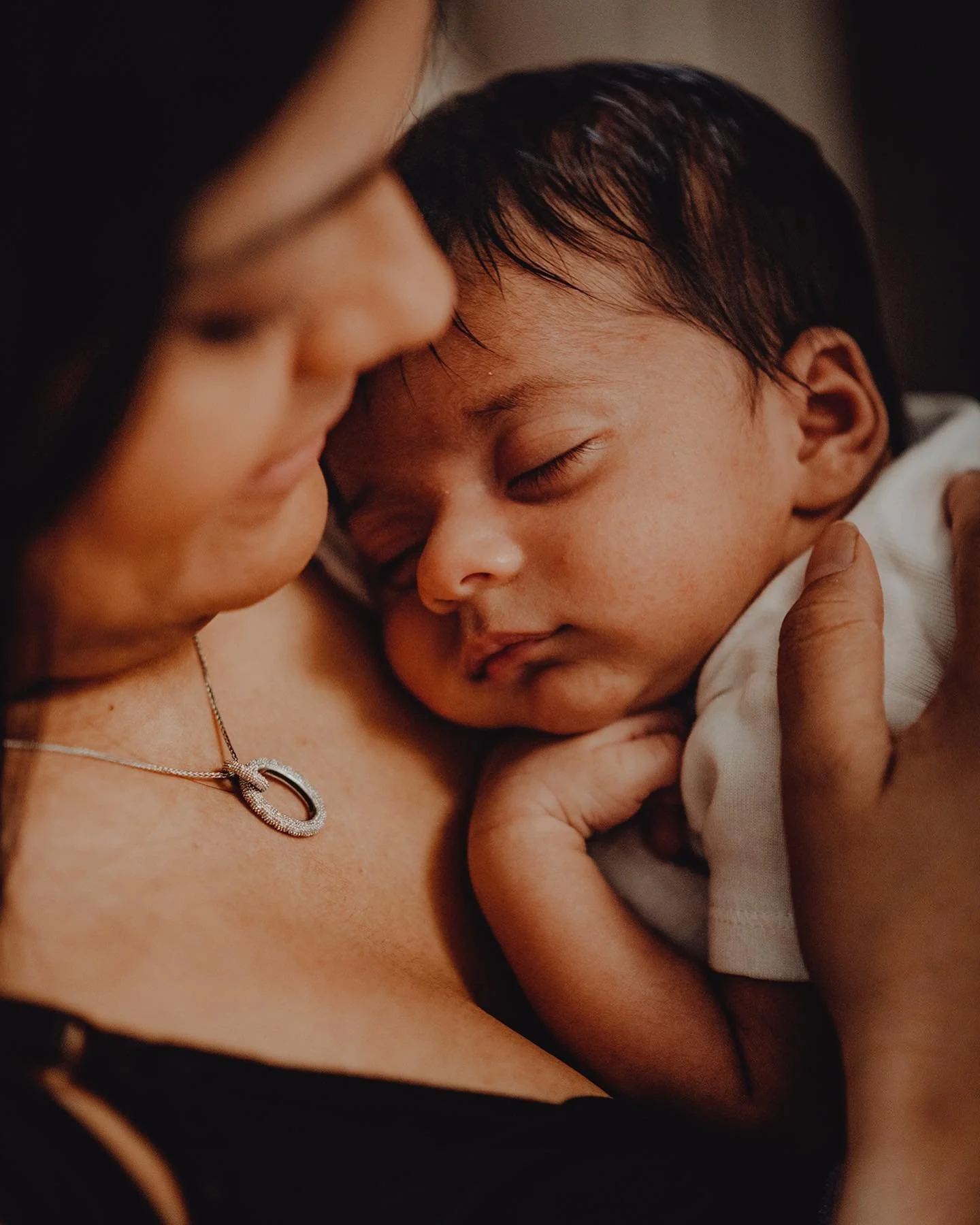 Mom holding her sleeping baby close to her chest.