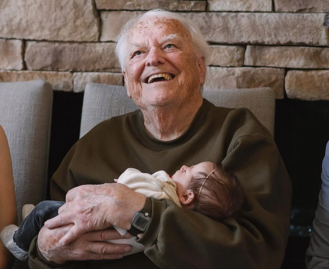 A documentary and yet cinematic photo of a great grandfather meeting his grandchild for the first time