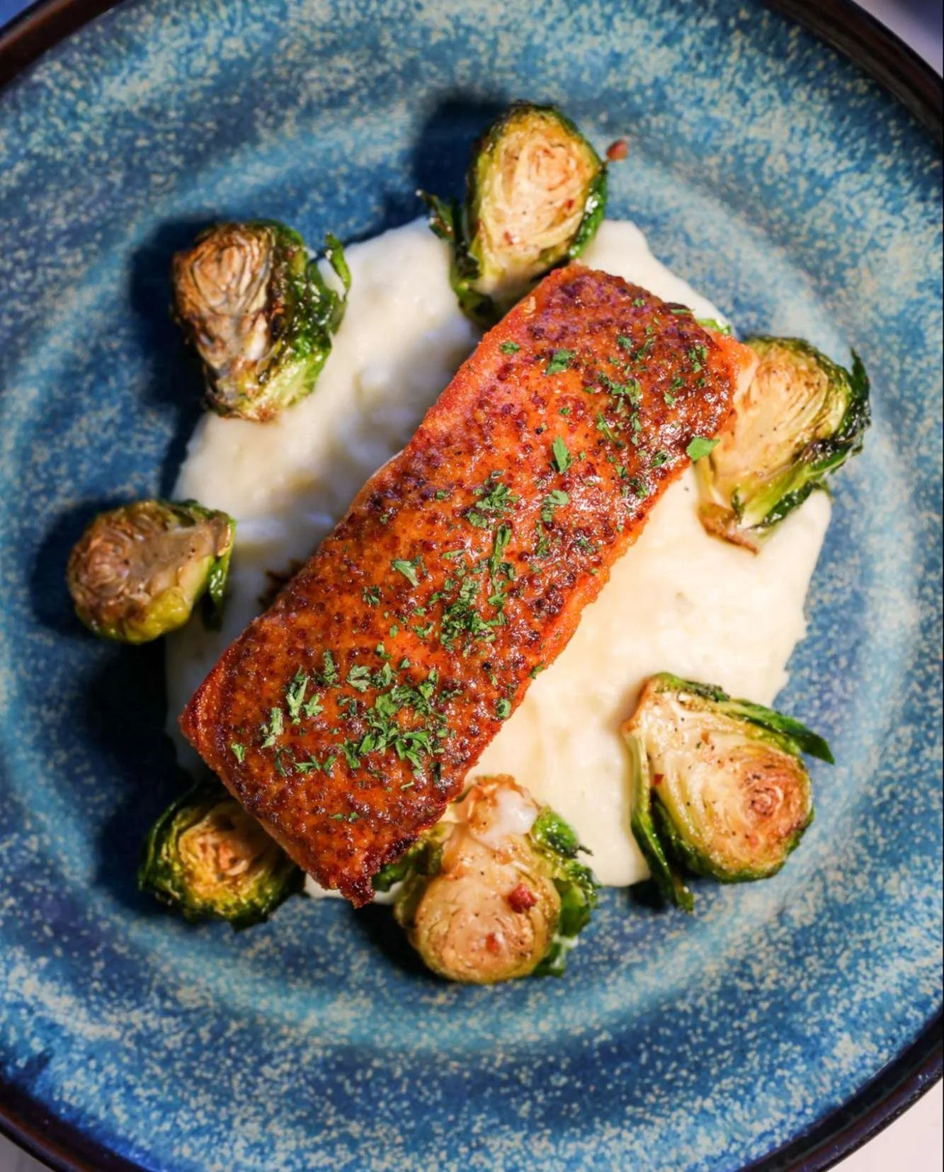 A fan favorite for a reason: our pan-roasted Faroe Island salmon, served with maple-mustard glaze, bacon-roasted Brussels sprouts, and creamy pommes pur&eacute;e 🐟