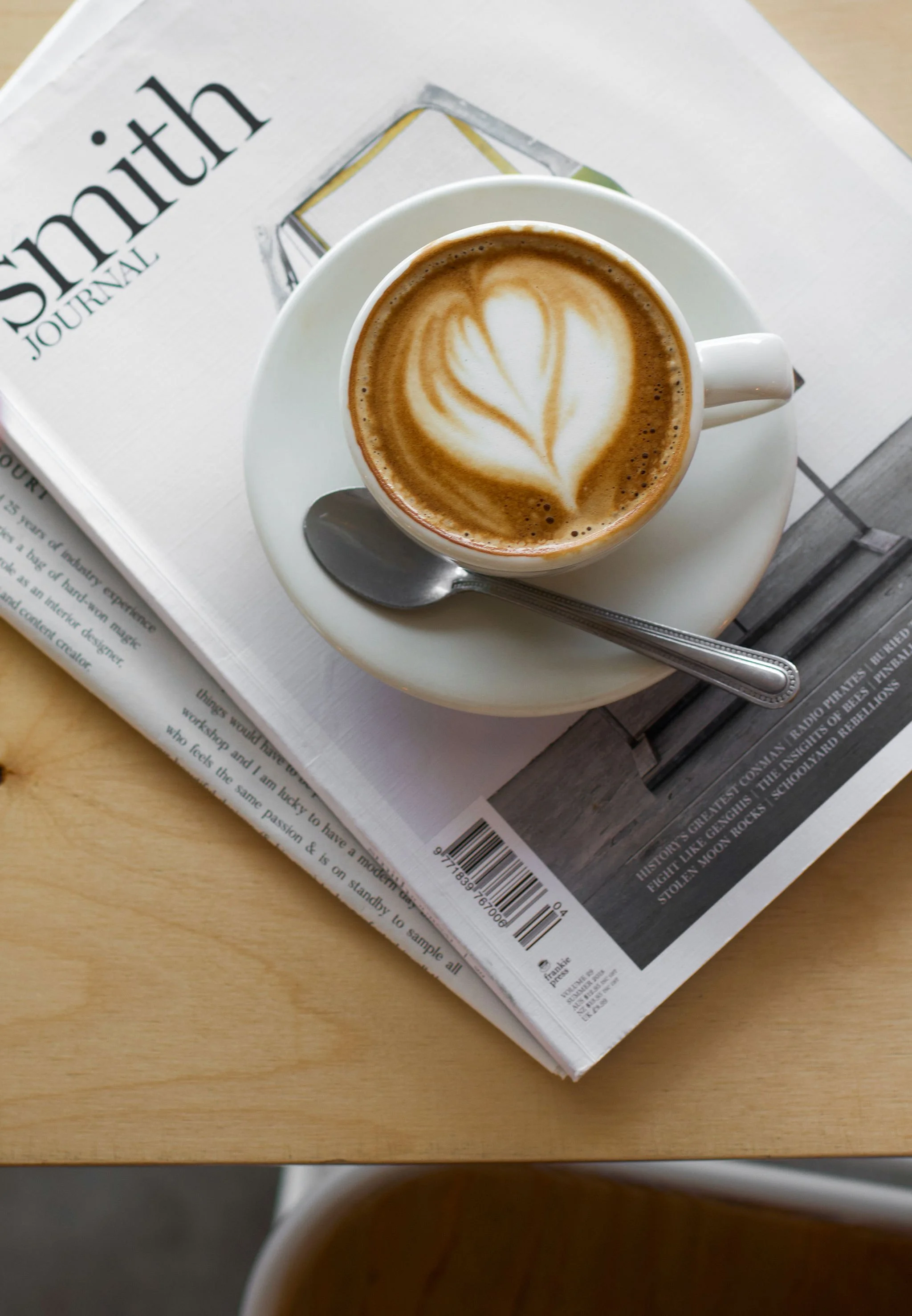 An inage of a desktop, with books and a cup of ezpresso sitting on top of them.