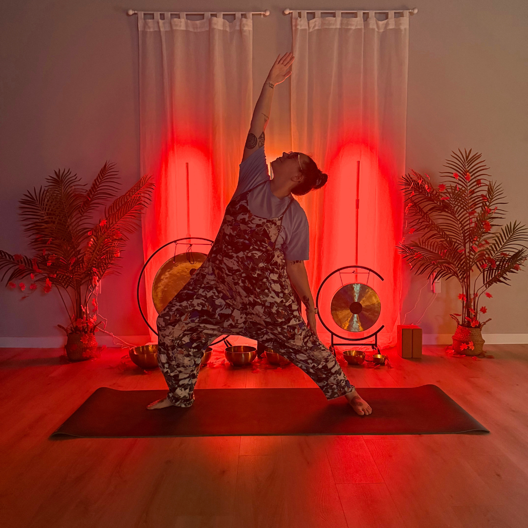 A yoga instructor leading a gentle slower stretch vinyasa flow in a mirror-free Gloucester County studio focused on nervous system regulation.