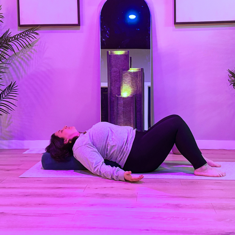 A yoga instructor leading a gentle slower stretch vinyasa flow in a mirror-free Gloucester County studio focused on nervous system regulation.