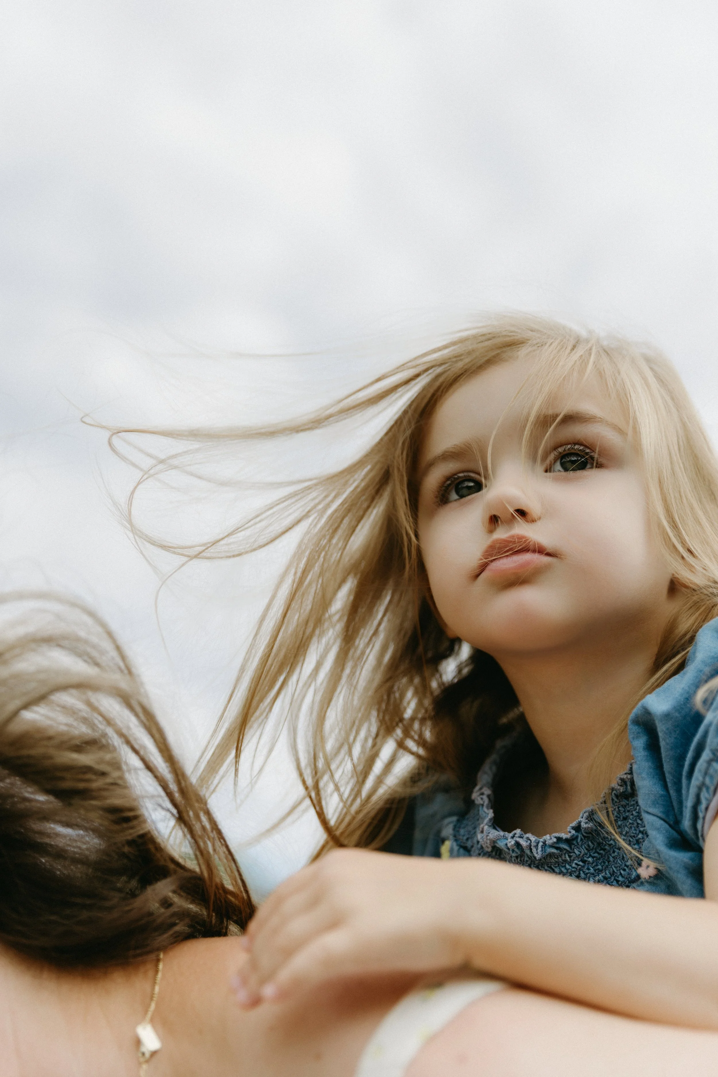 A family photograph featuring a young girl with blonde hair and blue eyes looking thoughtfully into the distance, in Central Park, by Maison Mancel.