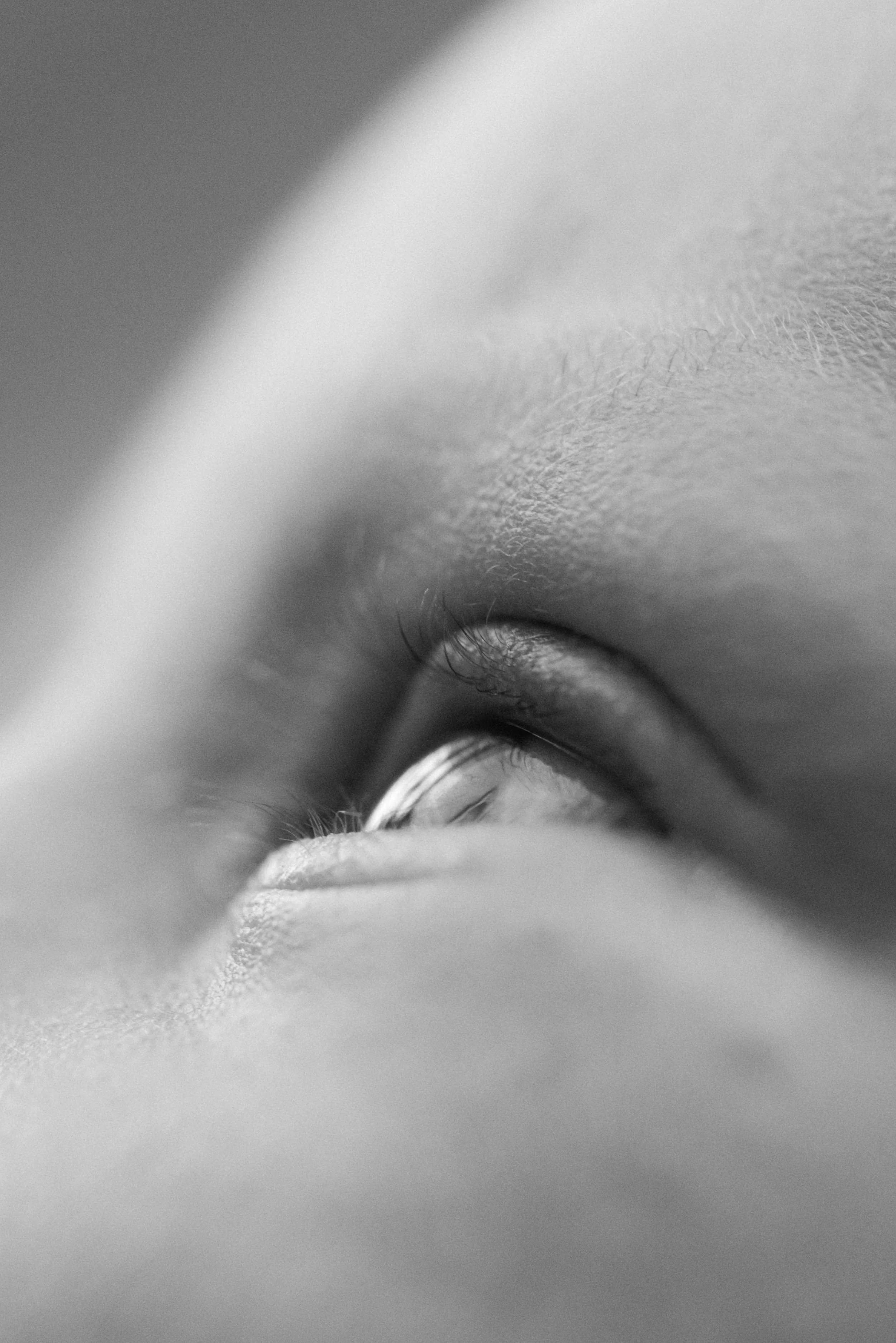 Close-up black and white photograph of a baby sleeping with a focus on the eye, nose, and part of the forehead. Photographed by Maison Mancel in NYC.