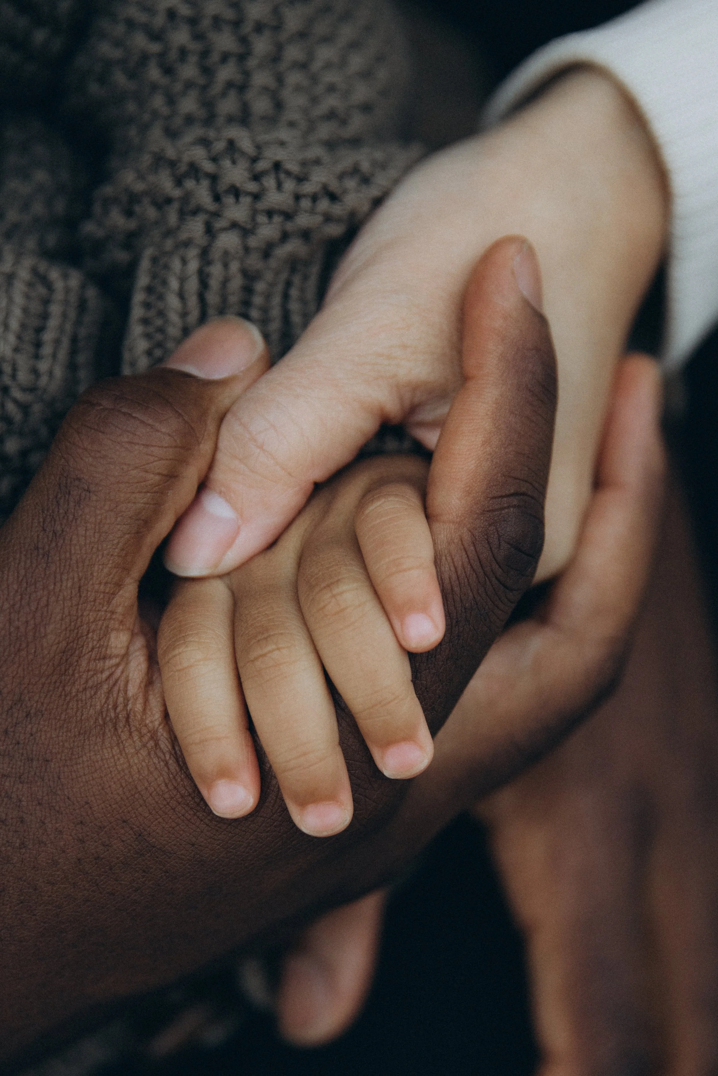 NYC Lifestyle family photograph - close-up of two hands holding each other, one darker-skinned and one lighter-skinned, symbolizing unity and diversity - by Maison Mancel.