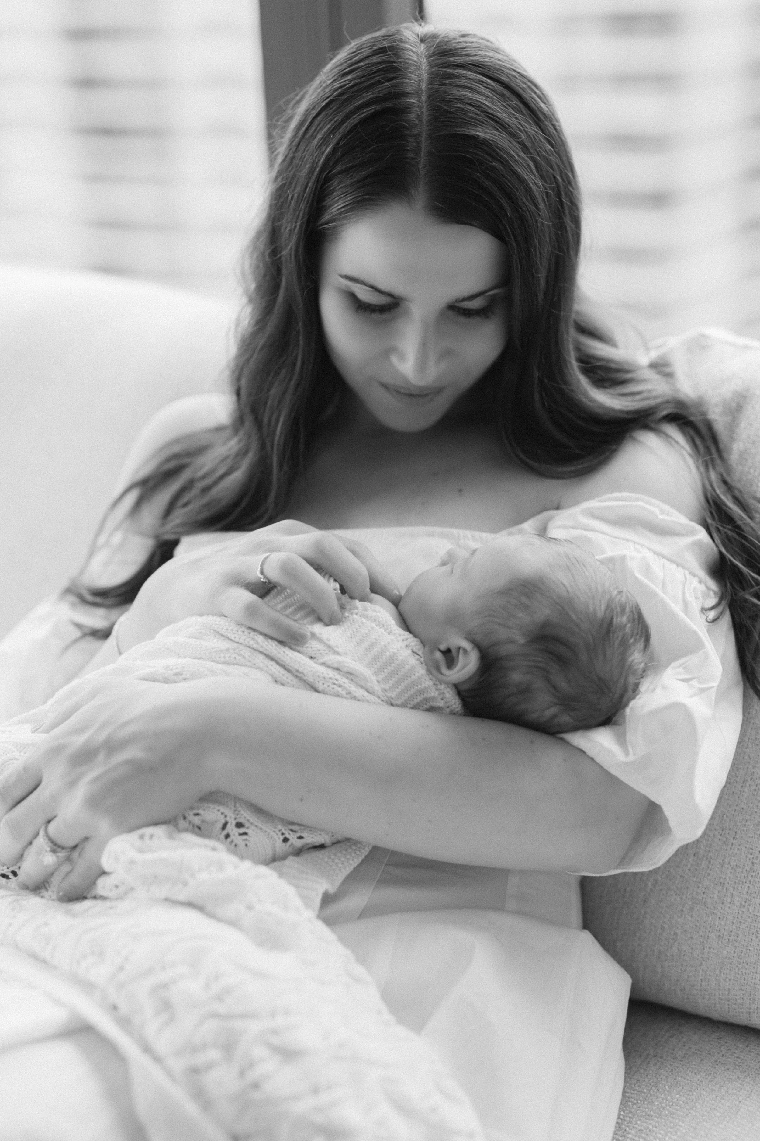 Black and white portrait of a mother with her baby in-home, both gazing at each other affectionately, photographed by Maison Mancel in NYC.