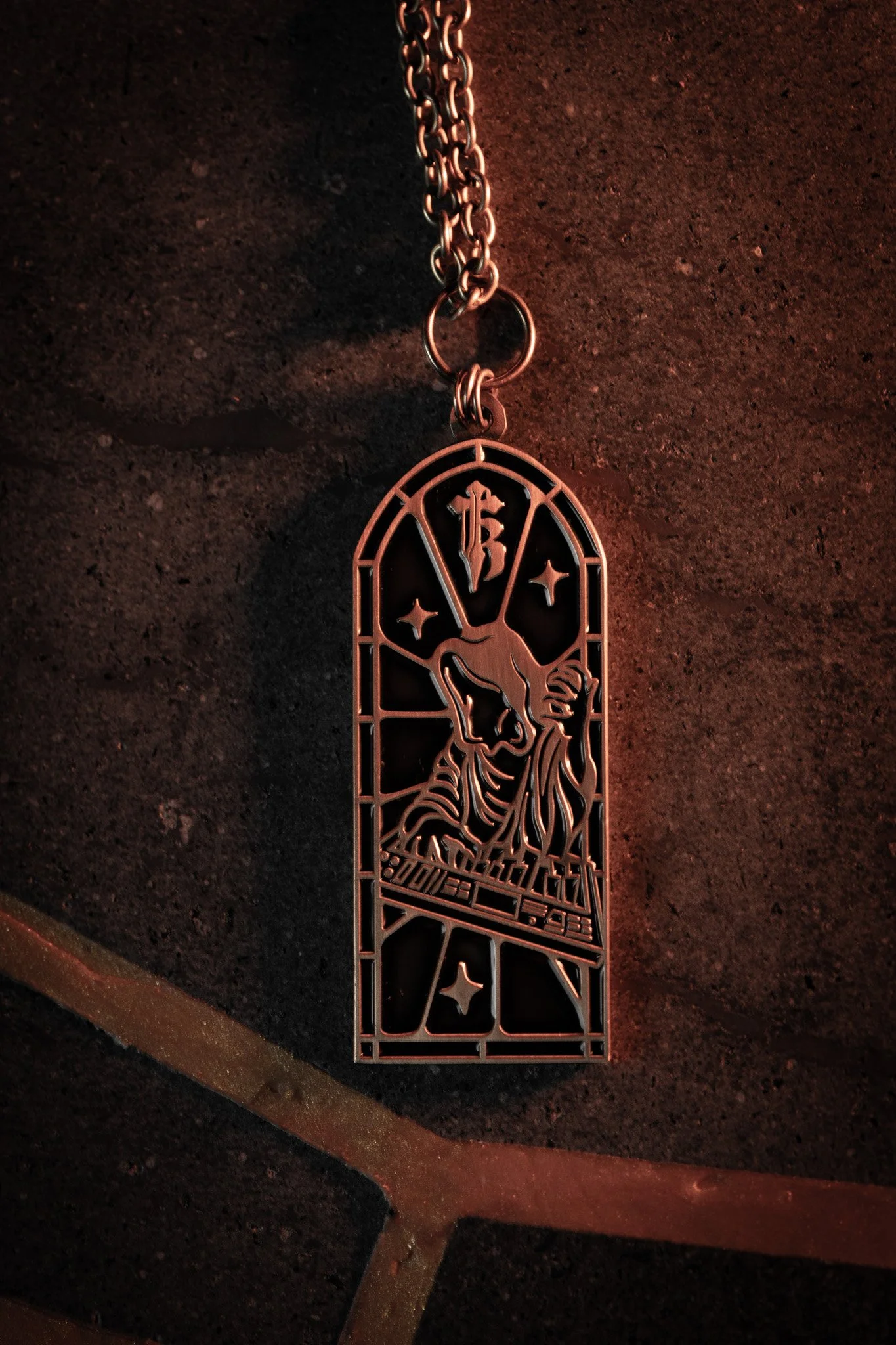 A metal keychain with a laser-cut design featuring a gnome with a long beard, wearing a pointed hat, and surrounded by stars, hanging from a chain. The background has a reddish-orange hue.