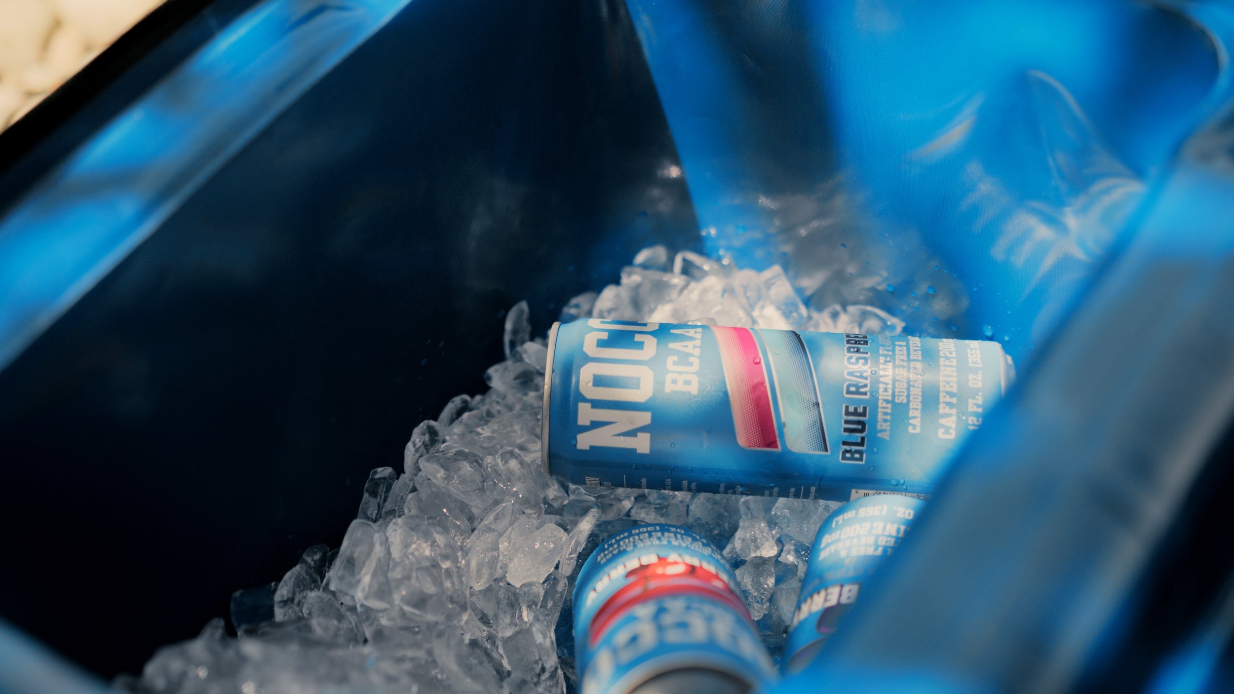 Cans of Blue Razz flavor energy drinks in a cooler filled with ice.