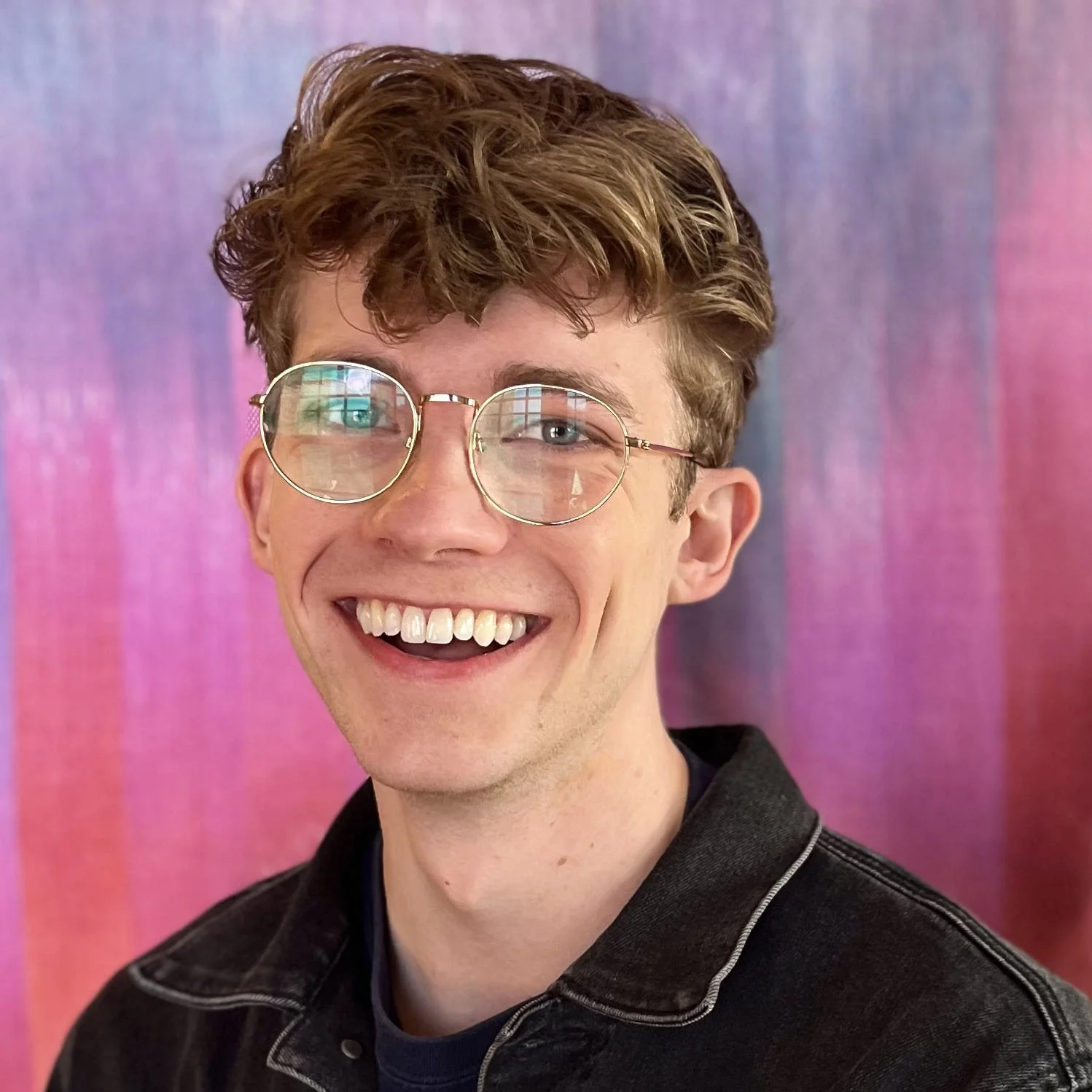 Person with glasses smiling against a colorful background