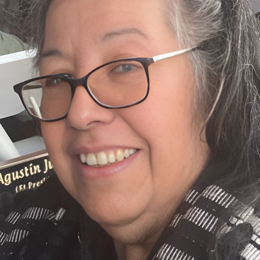 Close-up of a smiling person with glasses and black-and-white striped scarf.