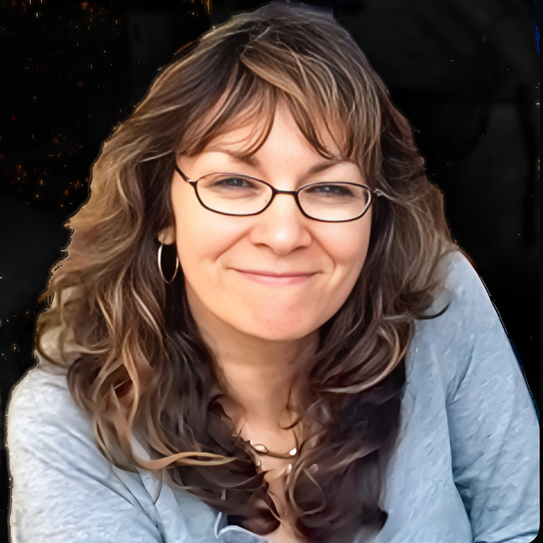 Smiling woman with glasses and curly hair wearing a blue shirt.