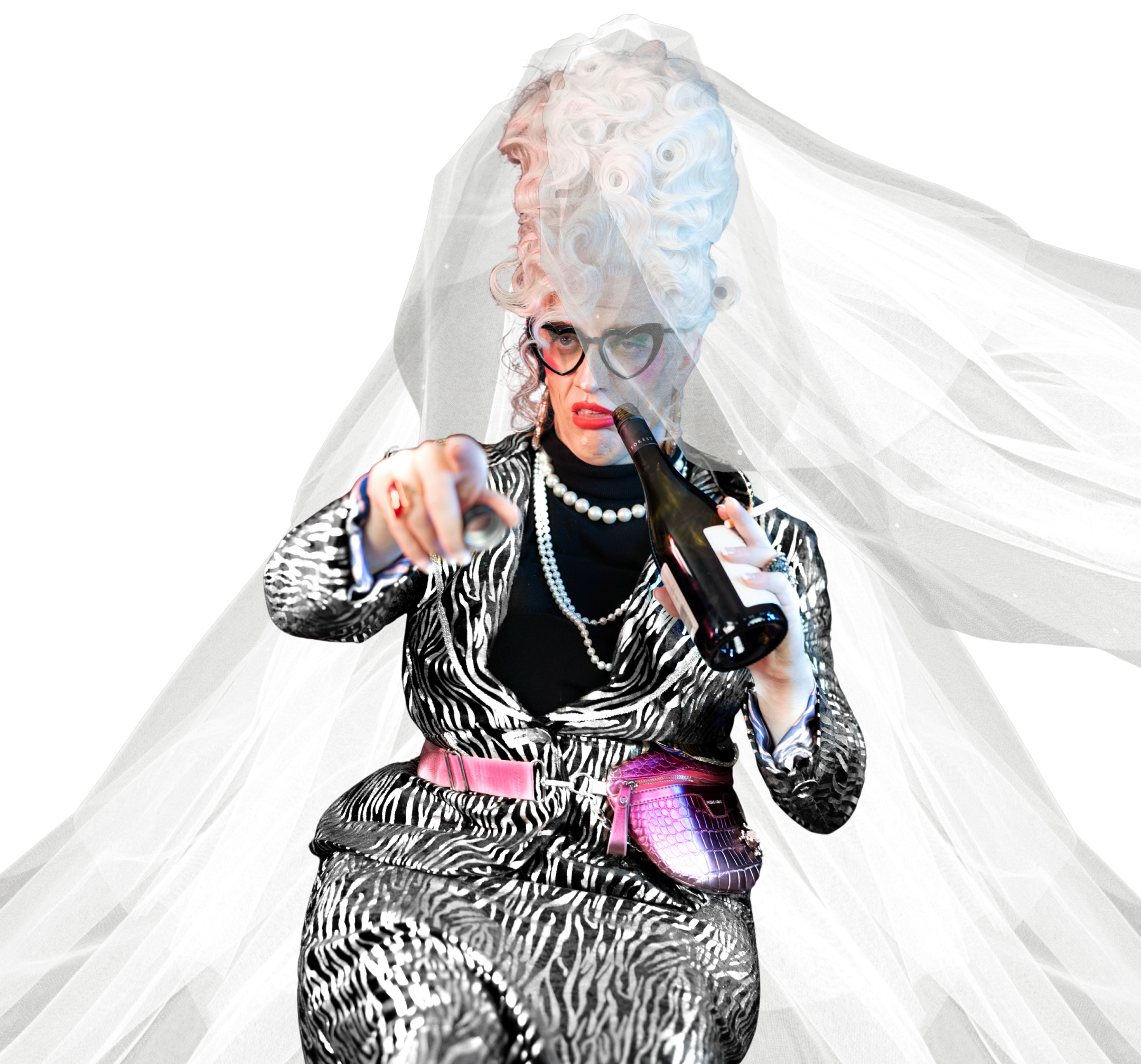 A person with curly, platinum blonde hair styled high, wearing black cat-eye glasses, a zebra print suit, and pearl jewelry, holds a beer bottle and points forward against a black background with white tulle fabric behind.