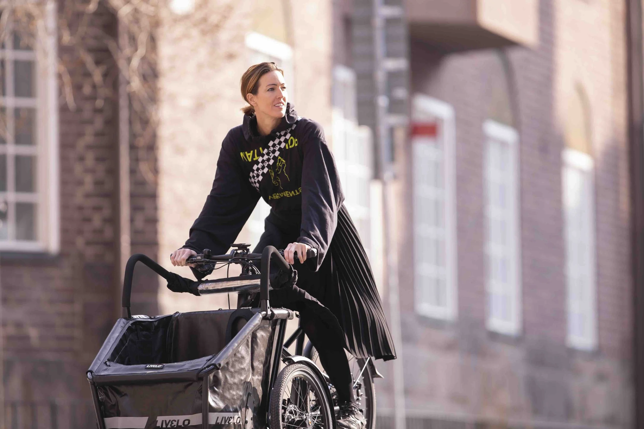 Kvinna cyklar till jobbet på en Livelo trehjulig familjecykel.