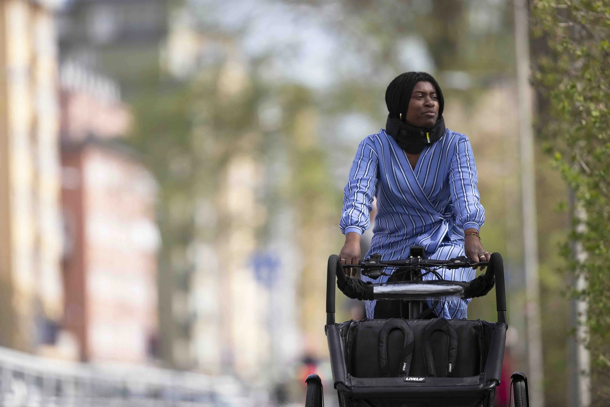 Kvinna tar sig fram på en Livelo elassisterad trehjuling i stadsmiljö.