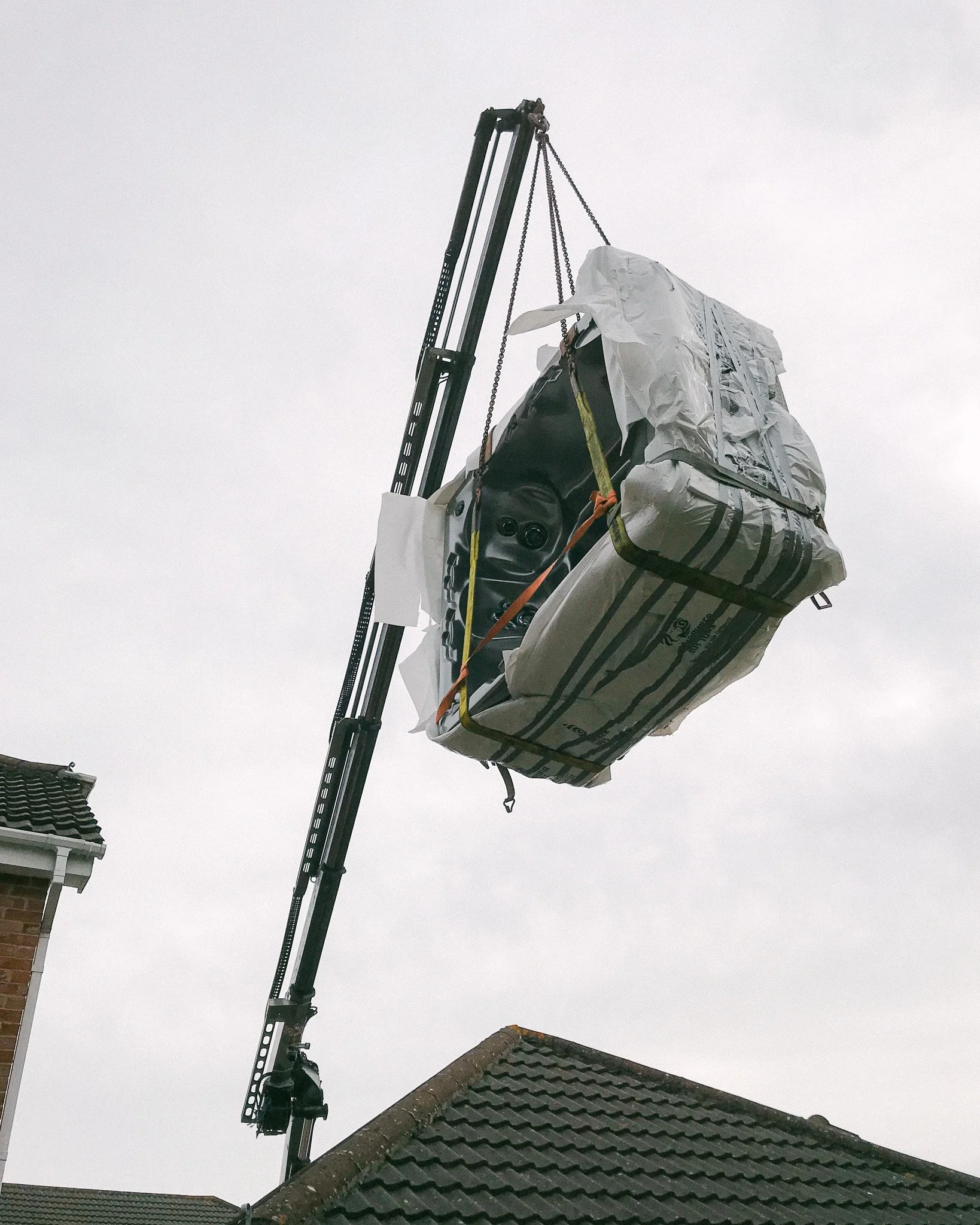 Chris Duck using his crane to delivery a hot tub into a back garden on an estate