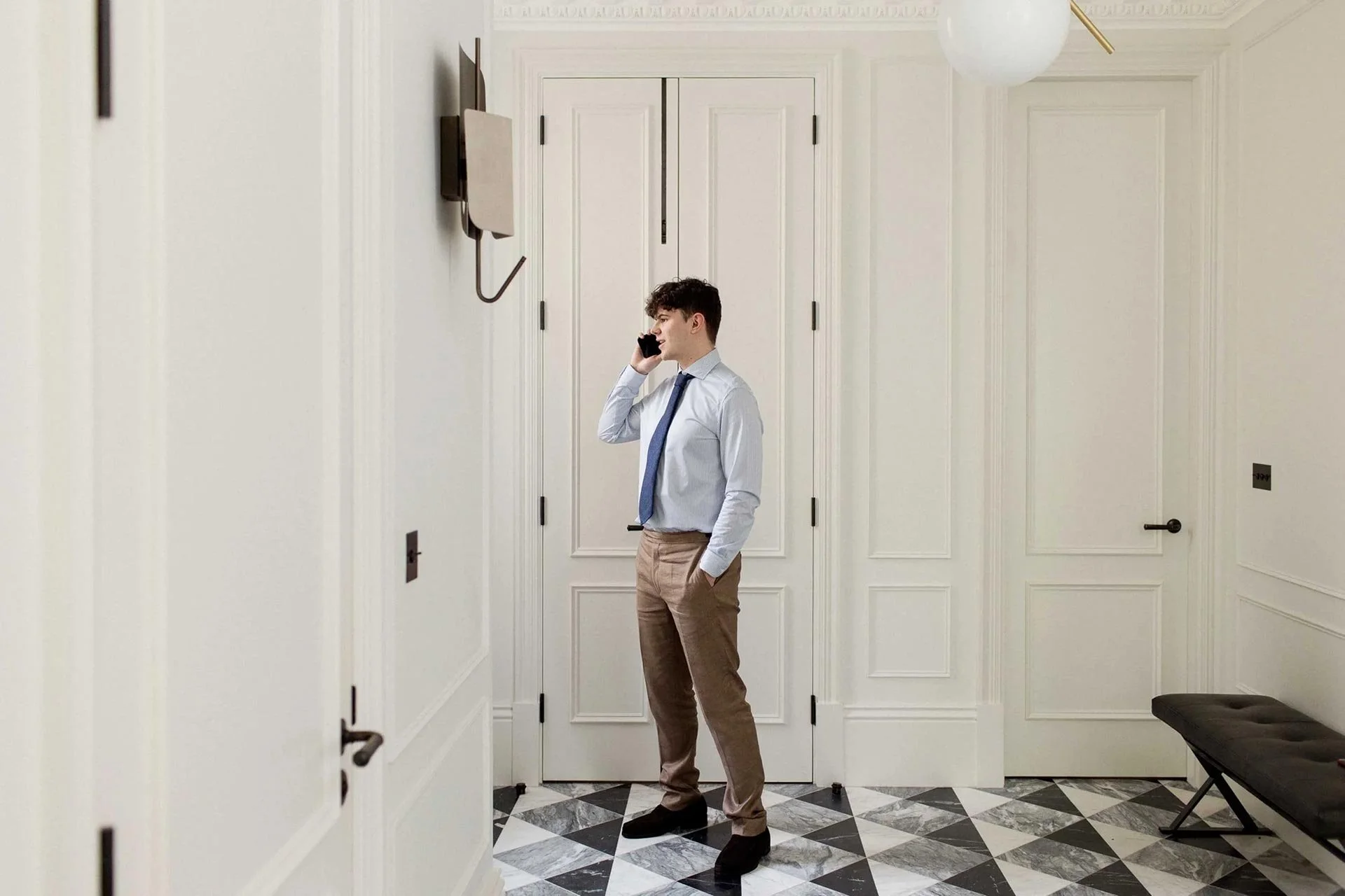 Man with blue shirt & tie and brown chinos talking on phone with HMRC at chartered accountants office in Mayfair, London