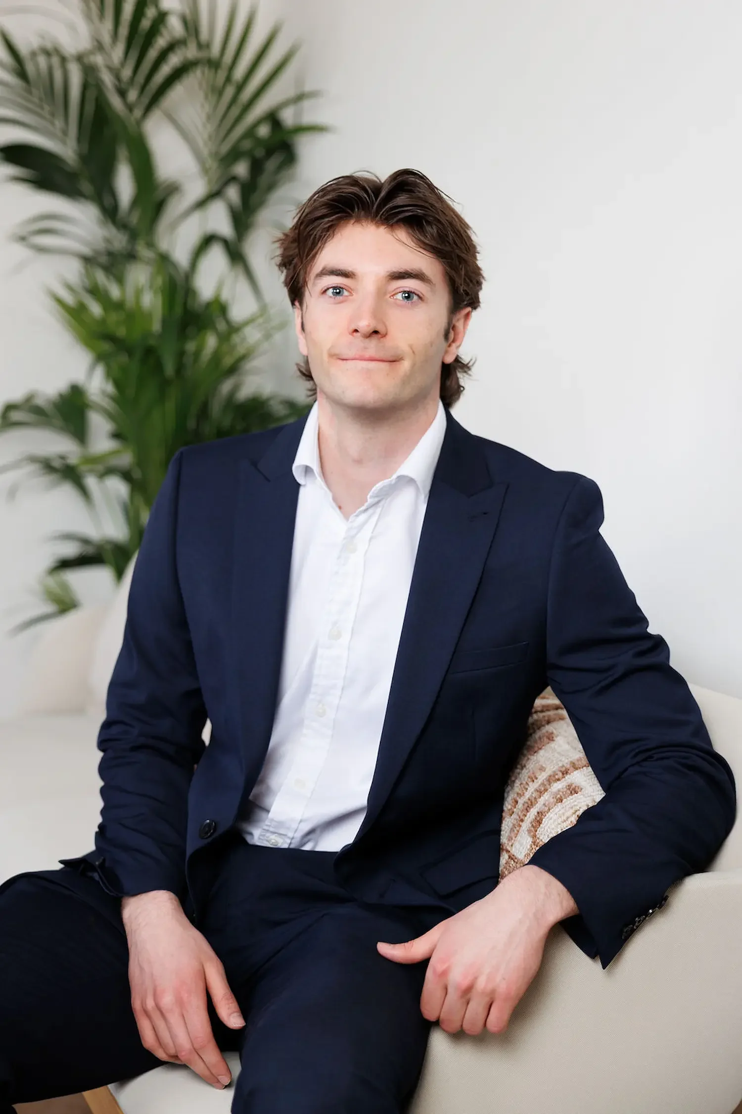 Sampson Fielding Junior Associate Patrick Hope smiling and sitting on a couch at their Central London advisory practice