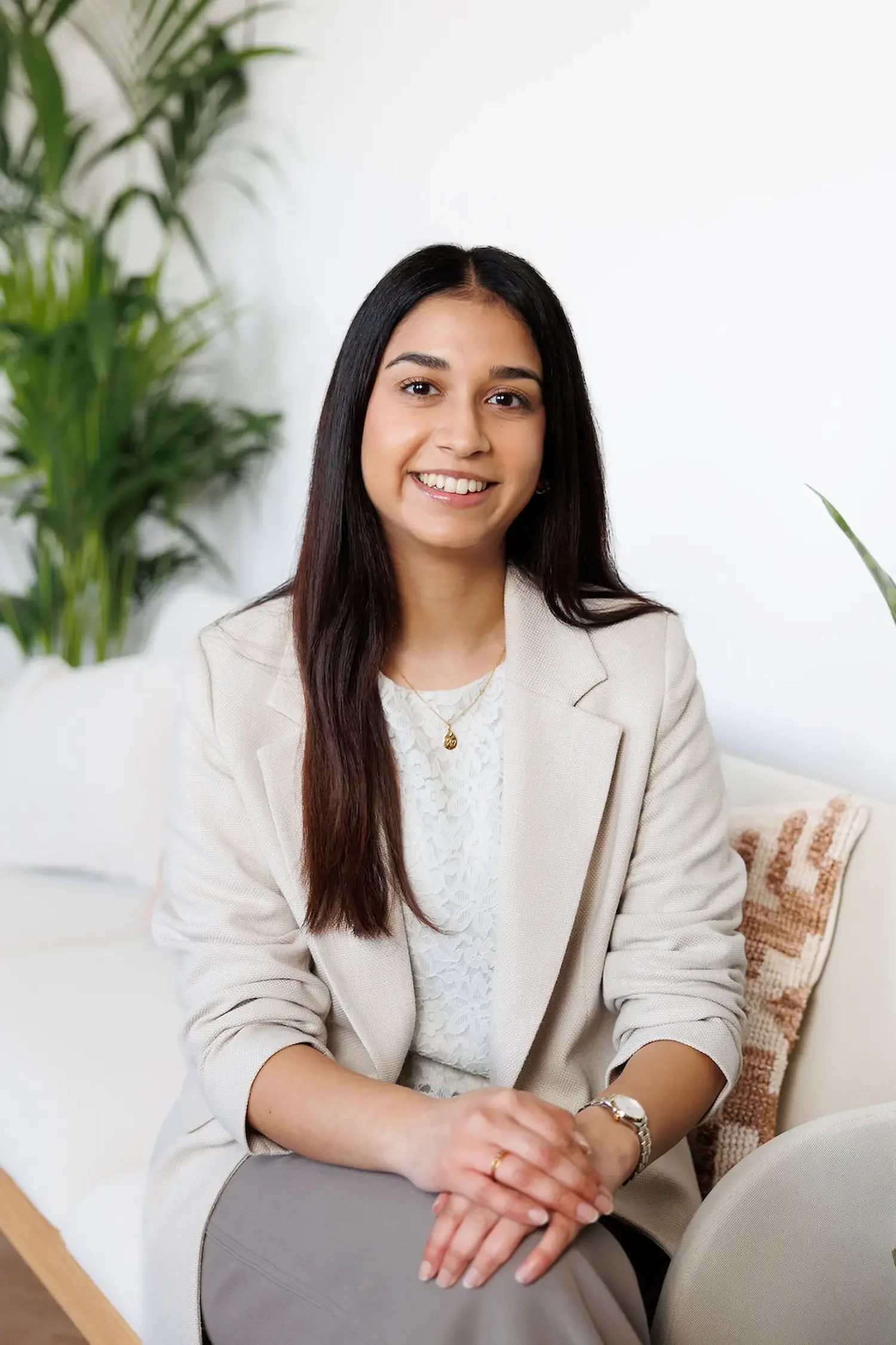 Sampson Fielding Junior Tax Associate Tiya Patel smiling and sitting on a sofa at their Central London practice
